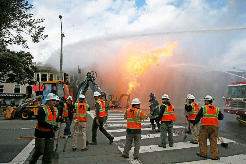 © Reuters. PG&E officials are seen as firefighters battle a fire following an explosion at Geary boulevard and Parker Avenue in San Francisco