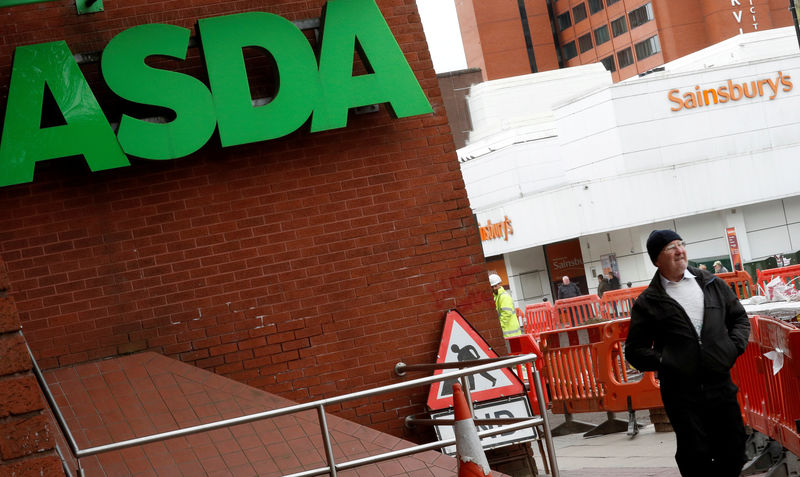 © Reuters. FILE PHOTO: A man walks past branches of ASDA and Sainsbury's in Stockport.