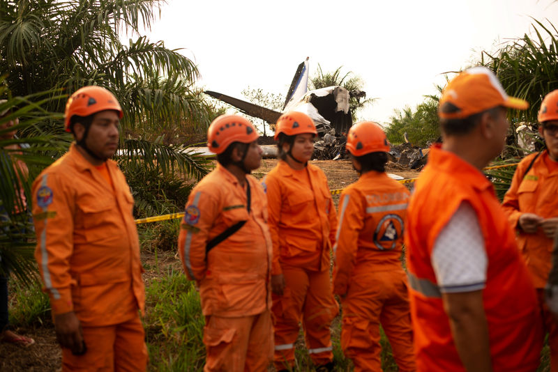 © Reuters. Members of the Colombian civil defense work where a plane crashed in the Colombian plains province of Meta, San Carlos de Guaroa