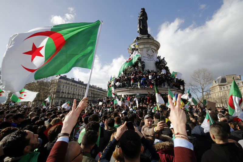 © Reuters. Manifestantes sostienen banderas de Argelia durante una protesta contra el presidente Abdelaziz Bouteflika en la Plaza de la República, París
