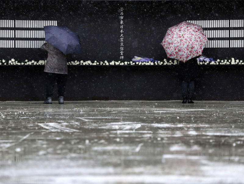 © Reuters. Bereaved people look for the name of their family members in the rain fall at Kamaishi memorial park in Kamaishi