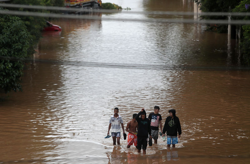 © Reuters. Hombres caminando en una calle inundada tras las fuertes en el barrio de Vila Prudente, en Sao Paulo