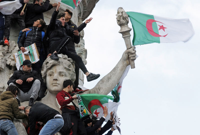 © Reuters. Manifestantes ondean banderas argelinas durante una marcha contra el presidente Abdelaziz Bouteflika en la Plaza de la República en París, Francia.