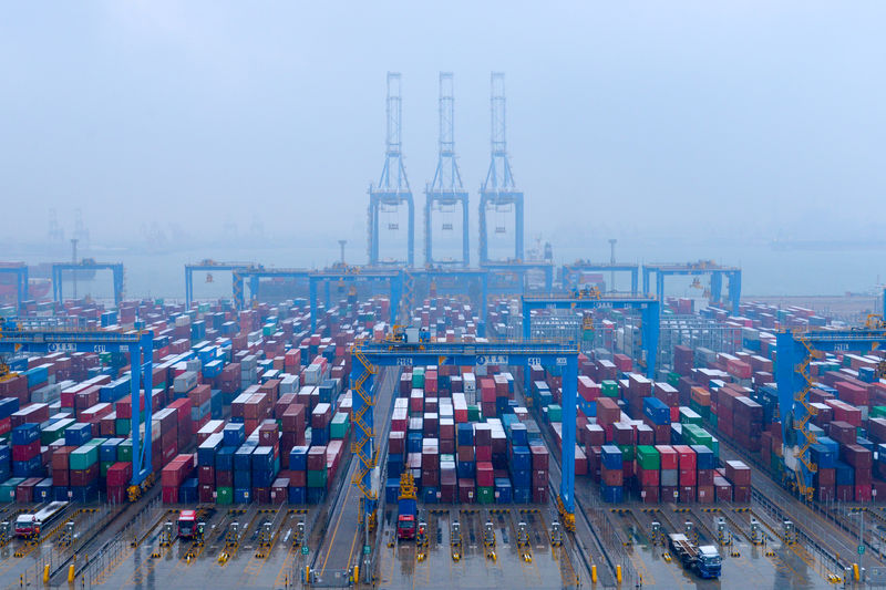 © Reuters. FILE PHOTO - Containers and trucks are seen on a snowy day at an automated container terminal in Qingdao port