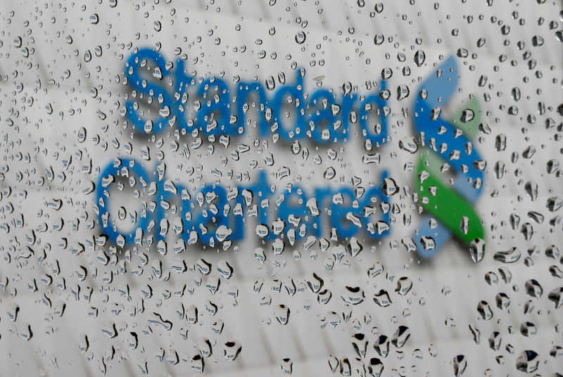 © Reuters. FILE PHOTO: A Standard Chartered logo at its headquarters is seen through a window with raindrops in Hong Kong