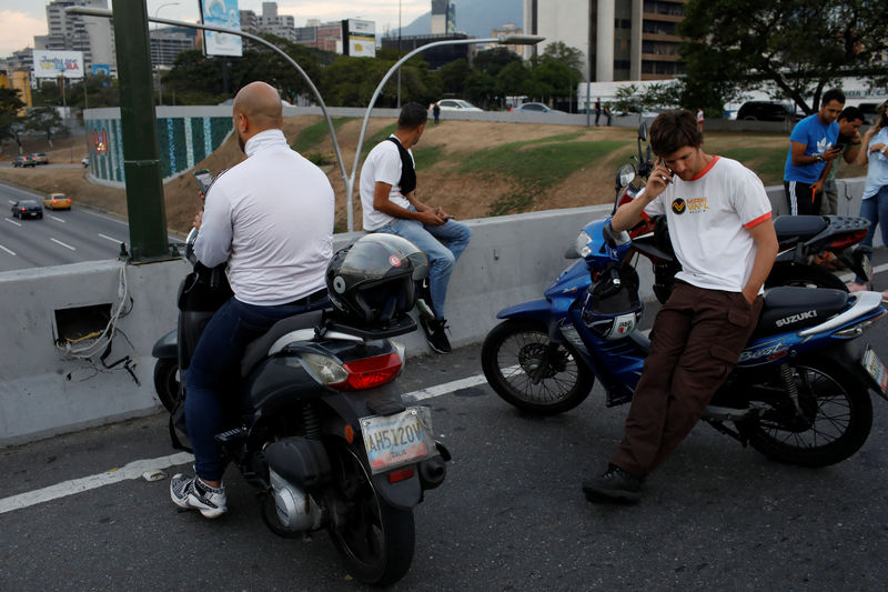 © Reuters. Motoristas se detienen a un lado de la autopista tratando de hallar señal de telefonía celular durante los apagones en Caracas
