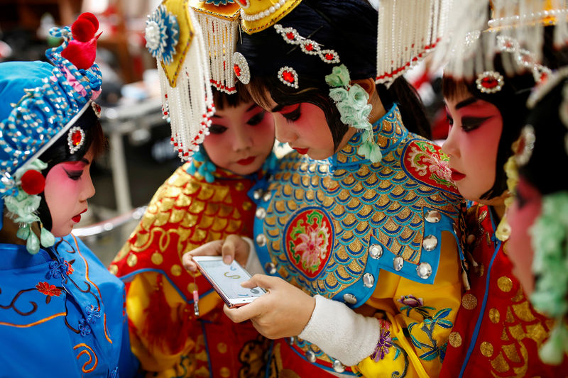 © Reuters. Niños juegan con su celular en un descando de un concurso de ópera tradicional china en Pekín. Imagen de archivo