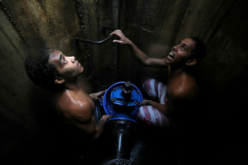 © Reuters. Locals collect water from an underground water main pipeline in Caracas