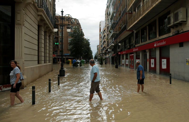 © Reuters. La gente camina por una calle inundada después de las lluvias torrenciales en Orihuela, España