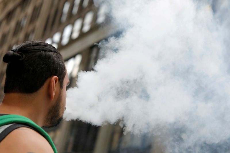 © Reuters. FILE PHOTO: A man uses a vape as he walks on Broadway in New York City