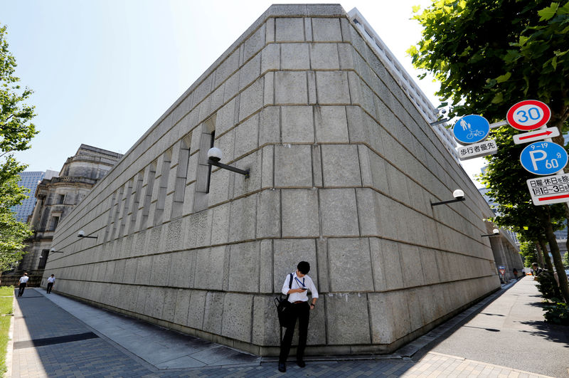 © Reuters. FOTO DE ARCHIVO: Un hombre mira un teléfono móvil frente al edificio del Banco de Japón en Tokio