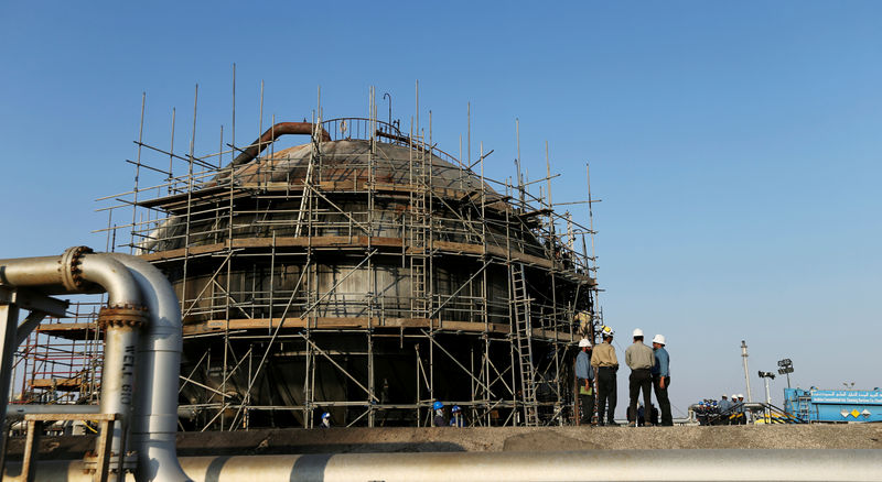 © Reuters. Workers are seen at the damaged site of Saudi Aramco oil facility in Abqaiq