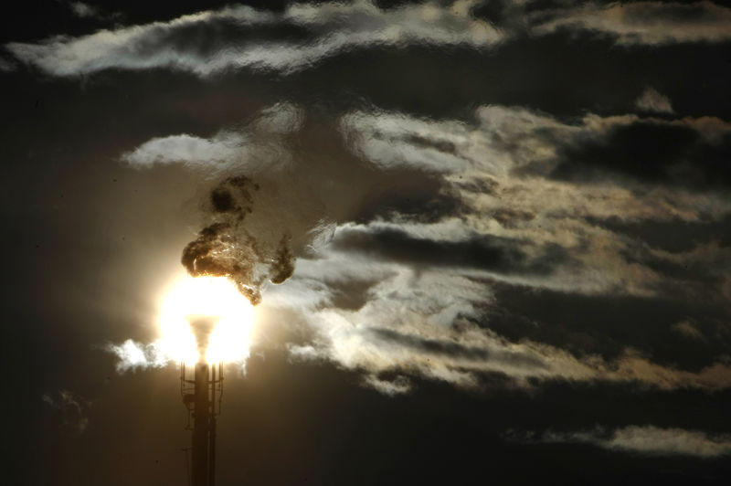 © Reuters. FILE PHOTO: A flare stack emitting fire is silhouetted against the sun at an oil refinery in Melbourne