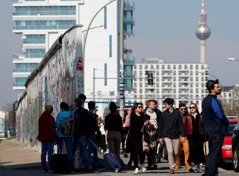 © Reuters. FILE PHOTO: People walk along the East Side Gallery, the largest remaining part of the former Berlin Wall in Berlin
