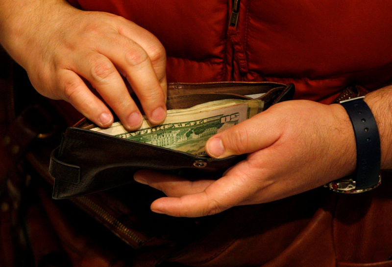 © Reuters. FILE PHOTO: A customer opens his wallet at a Macy's cash register on Black Friday in New York