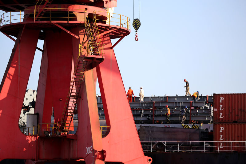 © Reuters. Men work on a cargo ship at a port in Lianyungang