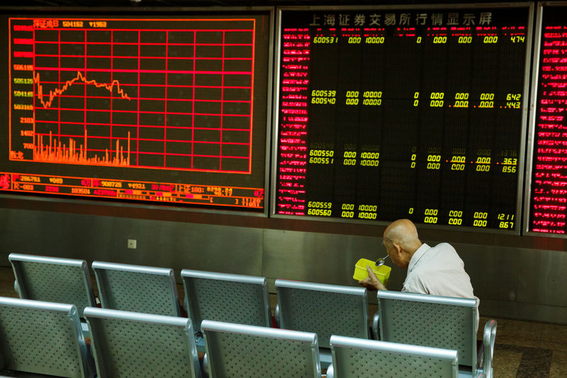 © Reuters. A man sits in front of a board showing market information at a securities brokerage house in Beijing