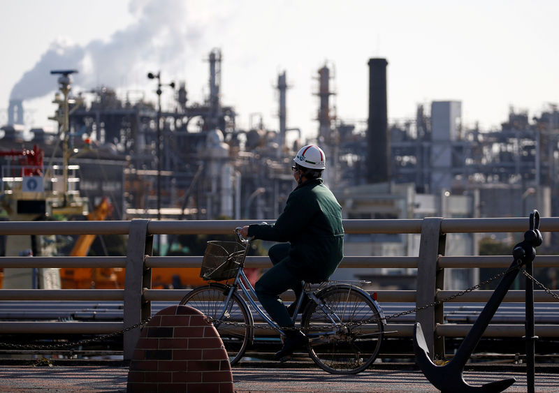 © Reuters. FILE PHOTO: A worker cycles near a factory at the Keihin industrial zone in Kawasaki