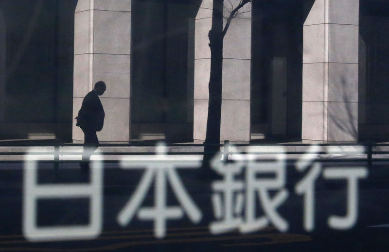 © Reuters. A man walking past a building is reflected in a sign board of the Bank of Japan building in Tokyo