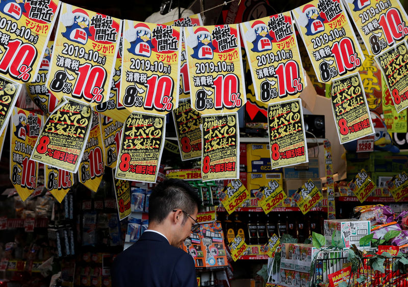 © Reuters. FOTO DE ARCHIVO: Un hombre elige productos debajo de pancartas que notifican el aumento del impuesto nacional a las ventas en una tienda en Tokio