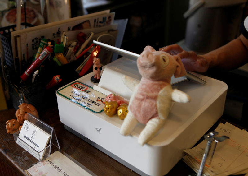 © Reuters. FOTO DE ARCHIVO: una empleada femenina ingresa los datos de ventas en una caja registradora estilo iPad, con un aviso encerrado en rojo que dice "impuestos excluidos", en el restaurante Fri-tei en Tokio