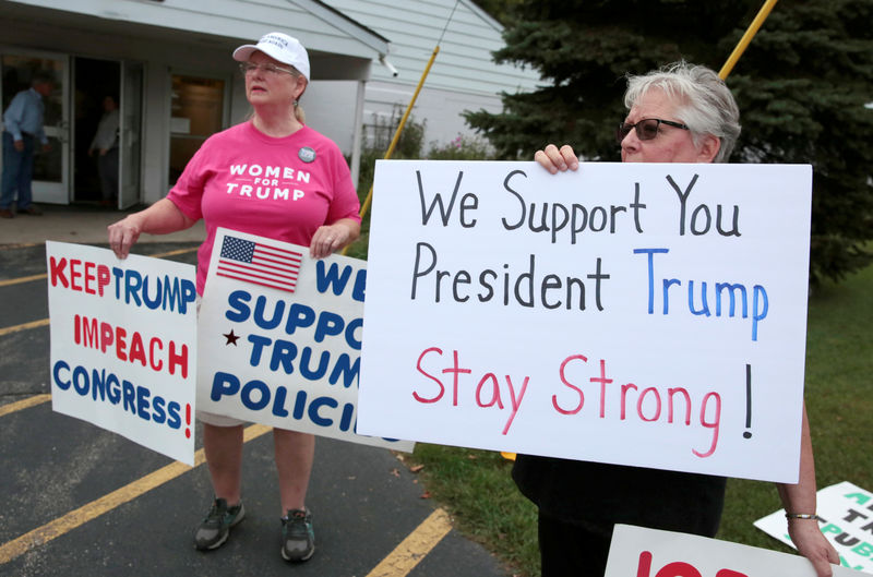 © Reuters. Pro-gun President Trump supporters hold signs outside a "End The Gun Violence" Town Hall in Michigan