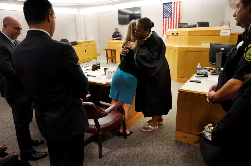 © Reuters. Amber Guyger leaps from her chair and gives Tammy Kemp a hug in Dallas