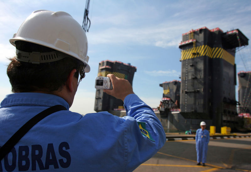 © Reuters. Un operaio Petrobas fotografa un suo collega su una piattaforma petrolifera offshore