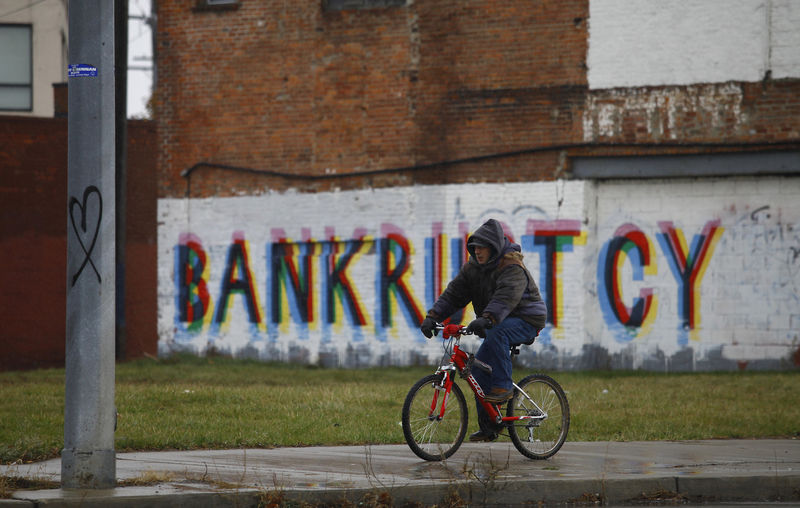 © Reuters. Un hombre monta su bicicleta pasando graffiti en Detroit