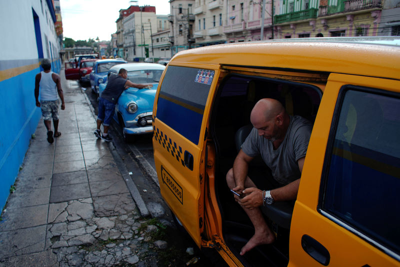 © Reuters. Taxi driver Alejandro Savieda, who has his car in a line for 5 days waiting for diesel to be delivered to a gas station, sits inside it in Havana