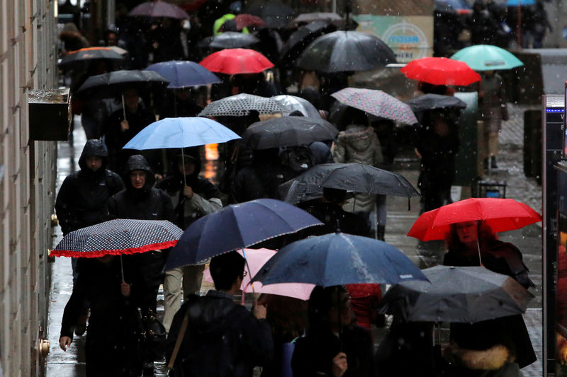 © Reuters. FILE PHOTO: People walk along Wall Street during the morning commute in the financial district during a winter nor'easter in New York