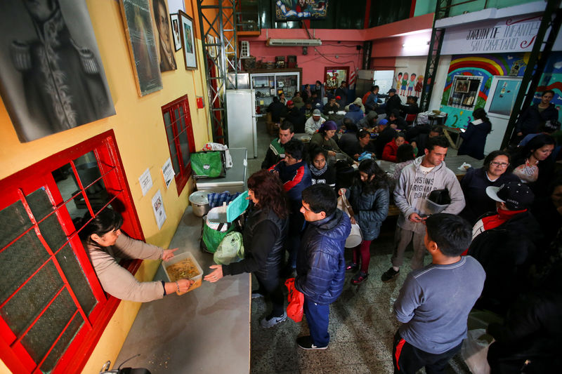 © Reuters. People line up to get stew ration at a soup kitchen in Buenos Aires