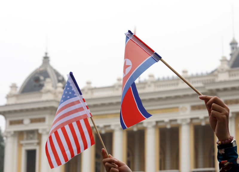 © Reuters. Residents hold US and North Korean flags while they wait for motorcade of North Korea's leader Kim Jong Un en route to the Metropole Hotel for the second US- North Korea summit in Hanoi