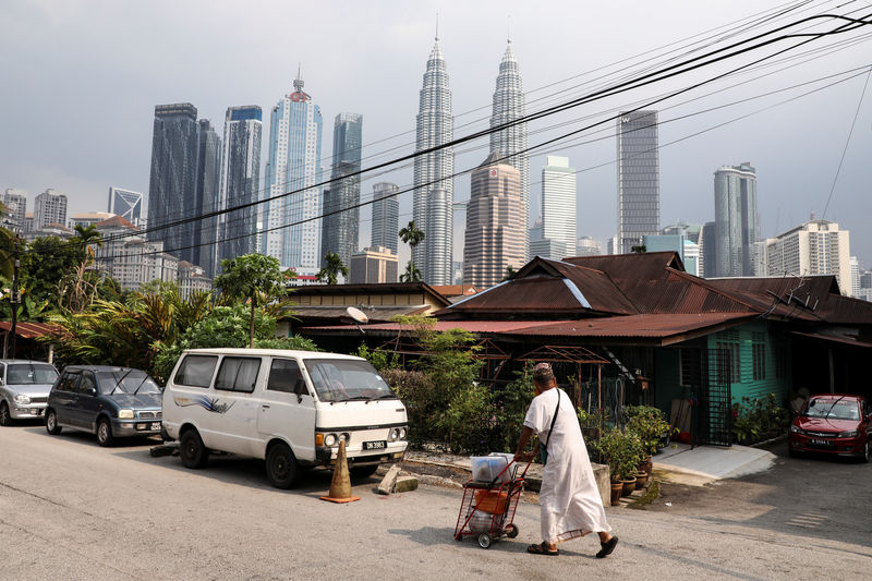© Reuters. A man walks past a house in Kuala Lumpur