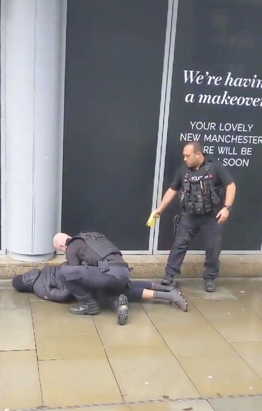 © Reuters. A police officer points a taser while the other holds a man down outside Arndale shopping center, where several people have been stabbed, in Manchester