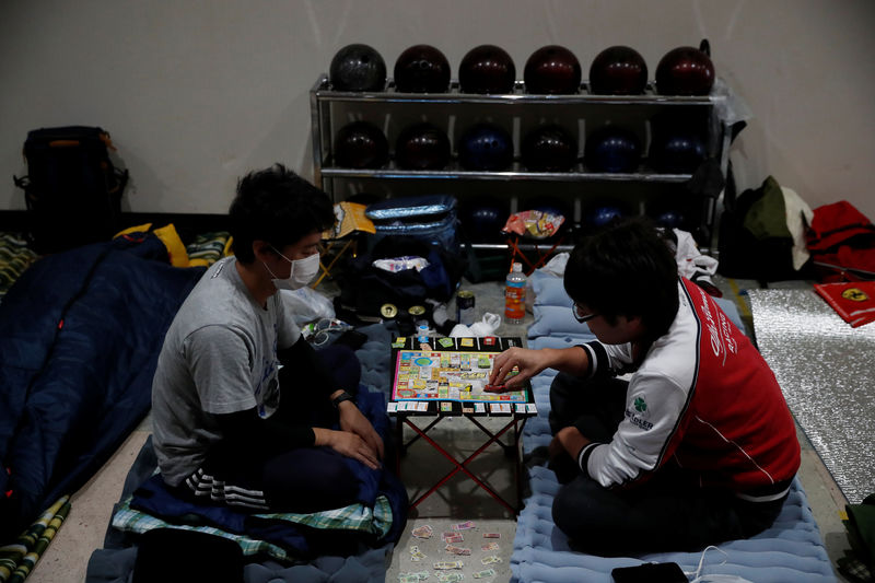 © Reuters. Men who evacuate from Typhoon Hagibis, play a game at a makeshift accommodation for spectators of Formula One Japanese Grand Prix at Suzuka Circuit in Suzuka