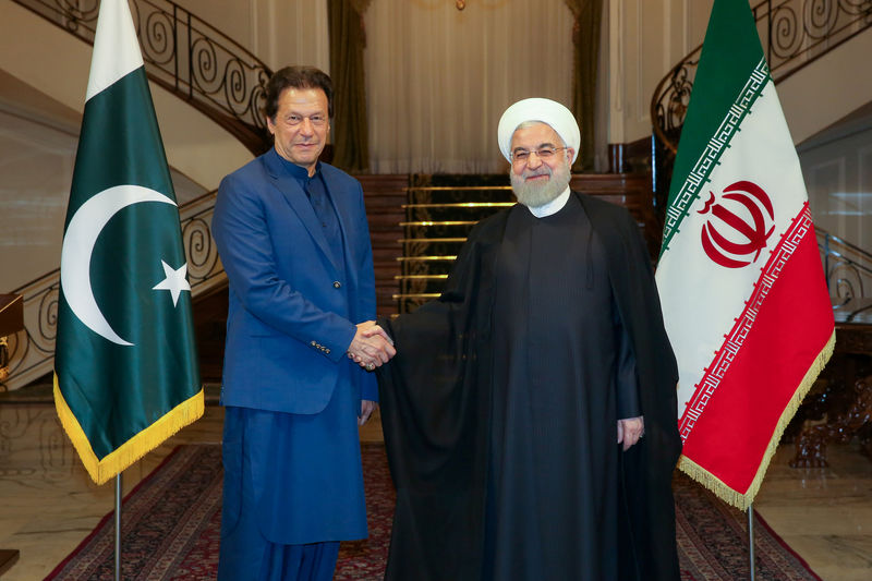 © Reuters. Iranian President Hassan Rouhani shakes hands with Pakistani Prime Minister Imran Khan in Tehran