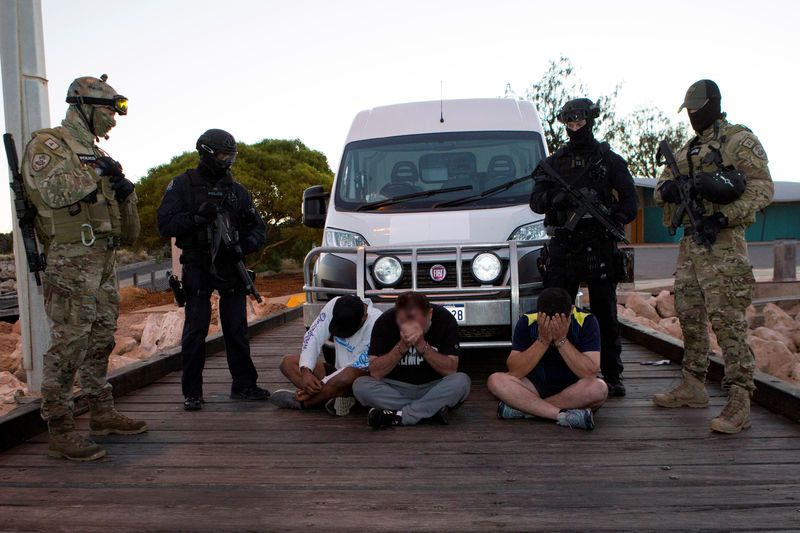 © Reuters. Police officers stand around suspects arrested during an operation that, according to police, resulted in the seizure of 1.2 tonnes of methamphetamine in Geraldton