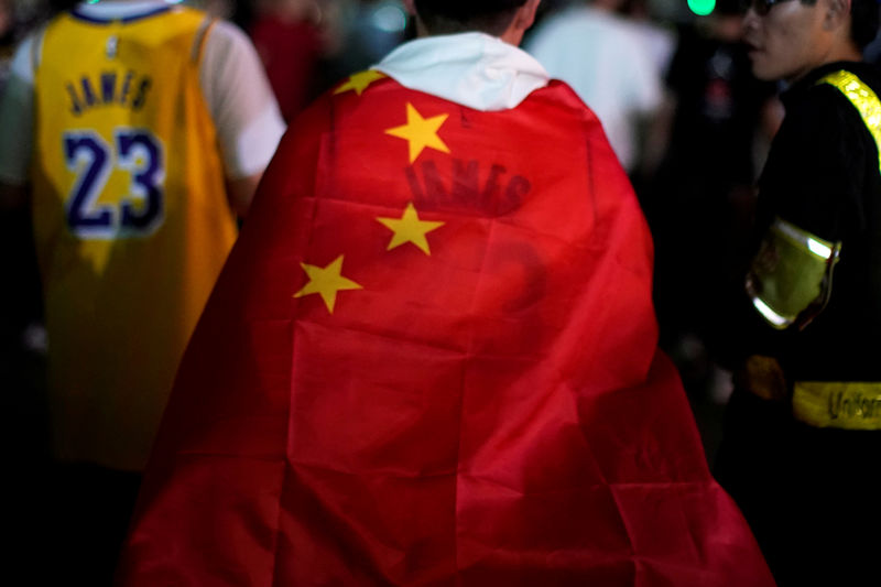 © Reuters. FILE PHOTO: Man wearing a LeBron James jersey wraps himself with a Chinese national flag before the NBA exhibition game between Brooklyn Nets and Los Angeles Lakers in Shanghai