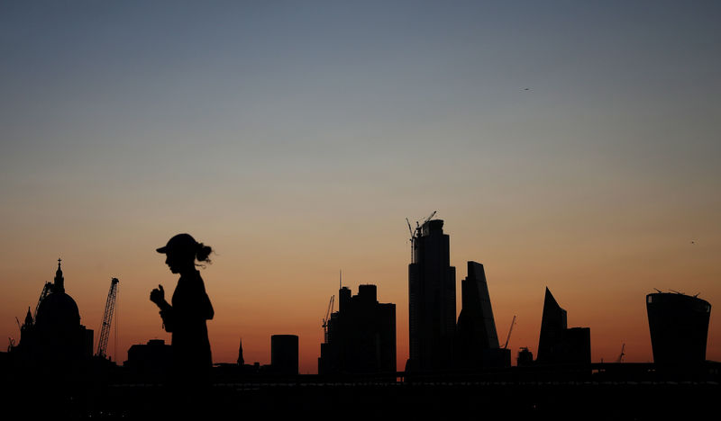 © Reuters. FILE PHOTO: A woman jogs as the sun rises behind the city of London financial district in London