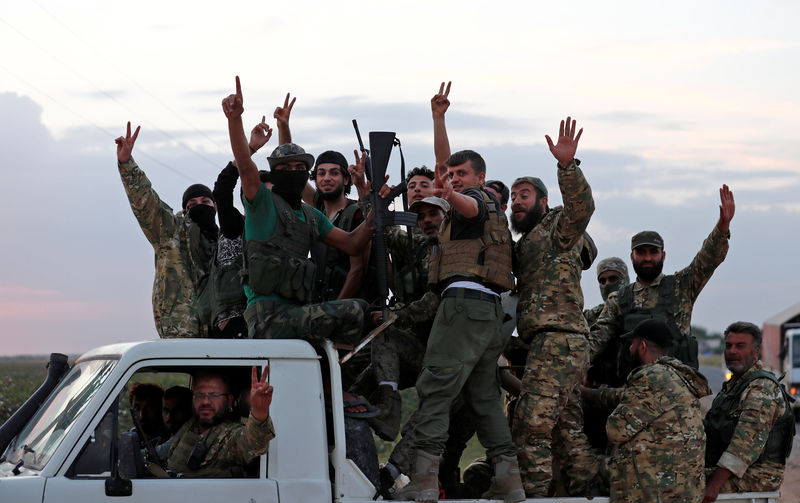 © Reuters. Turkey-backed Syrian rebel fighters drive on top of a truck to cross into Syria, near the border town of Akcakale