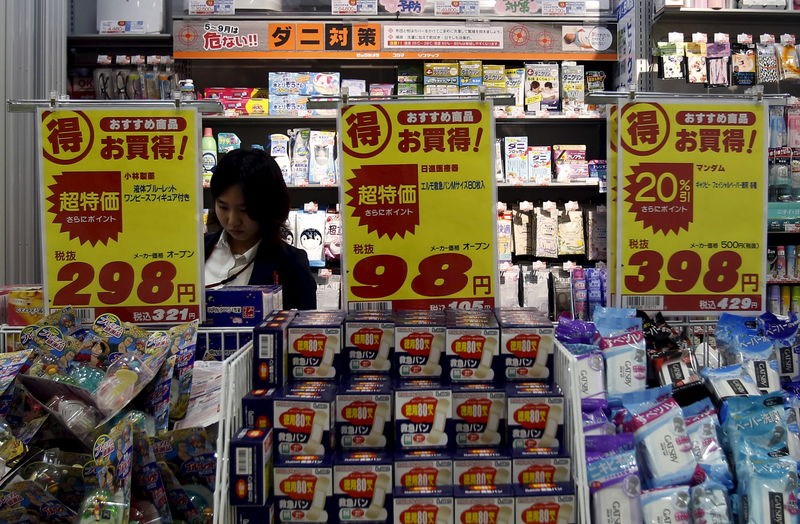 © Reuters. A shopper is seen between price boards at a drug store in Tokyo