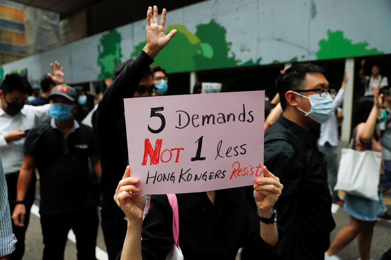 © Reuters. A demonstrator holds a sign while marching with others to protest against what they say is the abuse of pro-democracy protesters by Hong Kong police, in Central district, Hong Kong