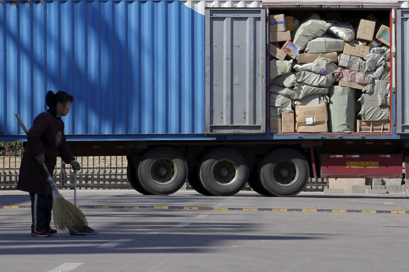 © Reuters. FILE PHOTO: A woman sweeps in front of a truck loaded with parcels at a YTO Express logistic centre in Beijing