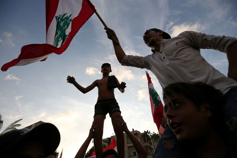© Reuters. Los manifestantes llevan banderas nacionales durante una protesta dirigida al gobierno por una crisis económica en la ciudad portuaria de Sidón