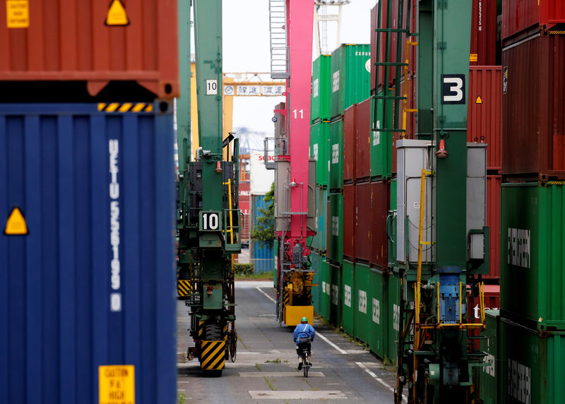 © Reuters. FILE PHOTO: A man in a bicycle drives past containers at an industrial port in Tokyo