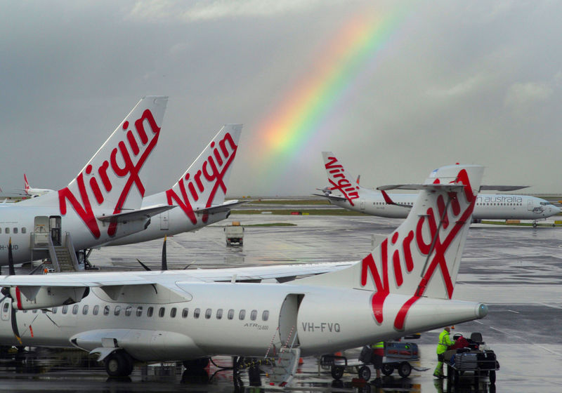 © Reuters. A rainbow from a passing rain shower sits over Virgin Australia aircraft at Sydney's Airport in Australia