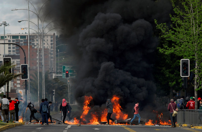 © Reuters. Manifestantes en Santiago de Chile cerca de una barricada en protesta por un alza de los precios del transporte