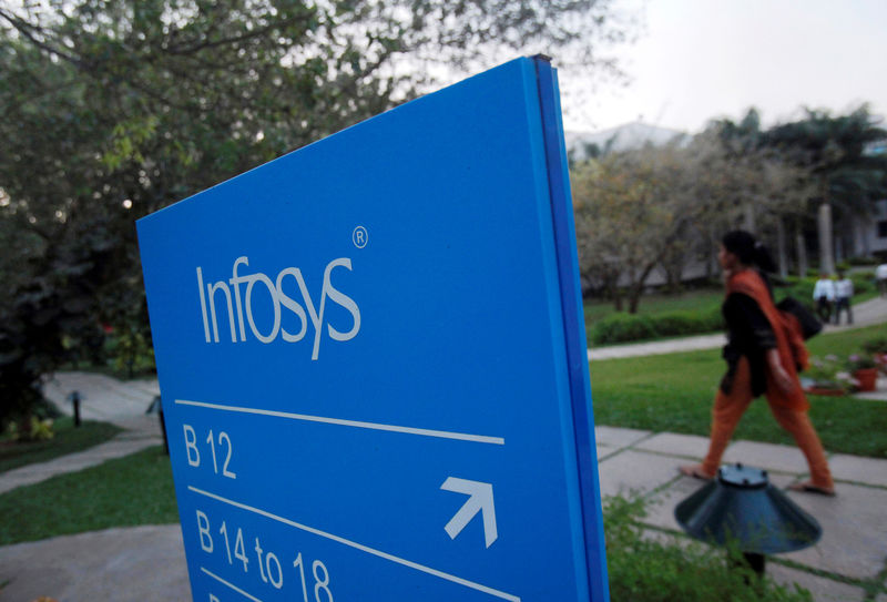 © Reuters. FILE PHOTO: An employee walks past a signage board in the Infosys campus at the Electronics City IT district in Bangalore