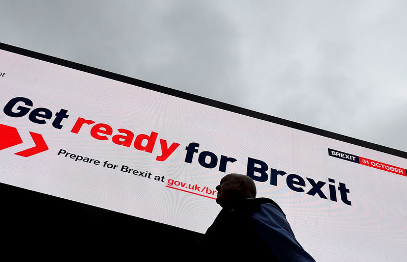 © Reuters. FOTO DE ARCHIVO: Un hombre pasa por una valla electrónica que muestra un anuncio de la campaña del gobierno británico para el Brexit en Londres